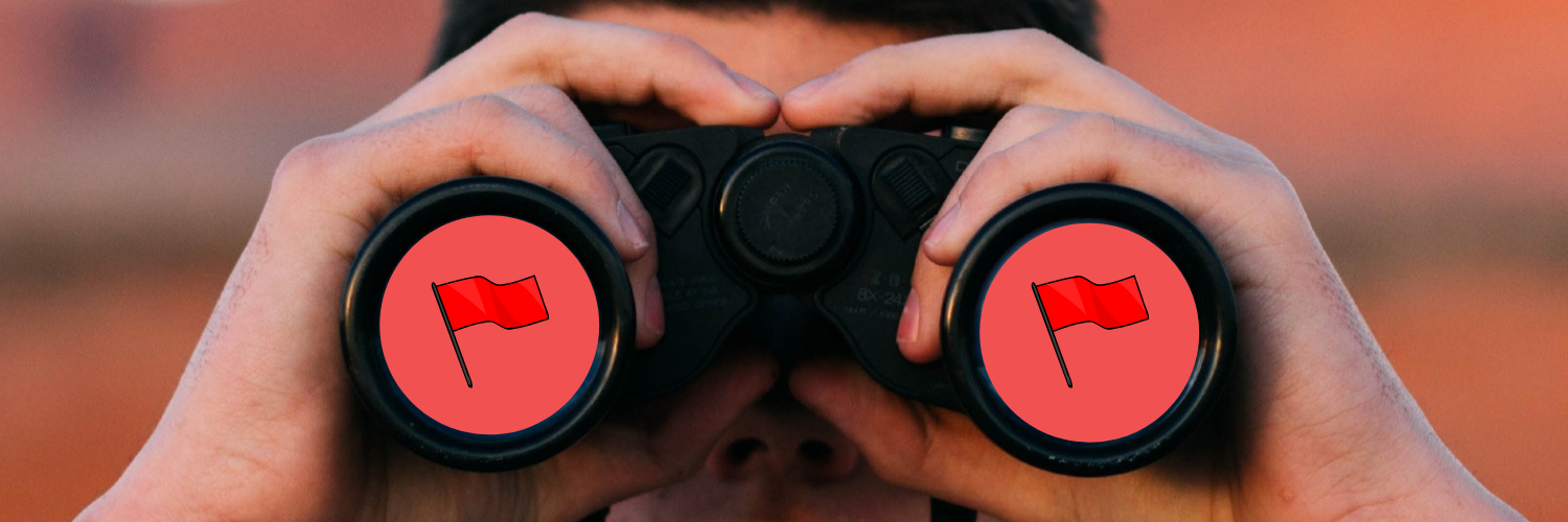 Close-up photo of a person holding binoculars. The lenses of the binoculars are red and have red flag symbols.